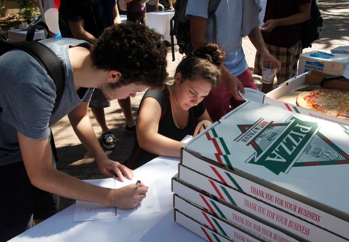College of Charleston students fill out a voter registration form while waiting in line for a slice of pizza at a Rock The Vote student registration drive on campus in Charleston, South Carolina, Thursday, September 27, 2012.