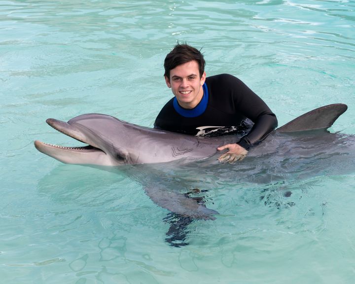 Performing artist Daniel Sahyounie grabs Kali, a bottlenose dolphin at SeaWorld San Diego's Dolphin Point in 2014.