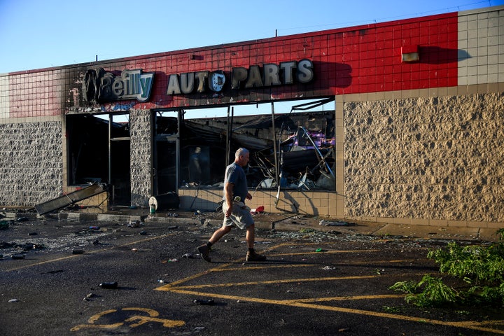 A man walks by an O'Reilly Auto Parts store that was destroyed during protests following a police shooting in Milwaukee, Wisconsin.