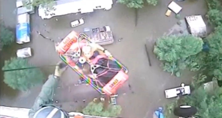 An aircrew from Coast Guard Air Station New Orleans rescues three people from a rooftop in Baton Rouge.