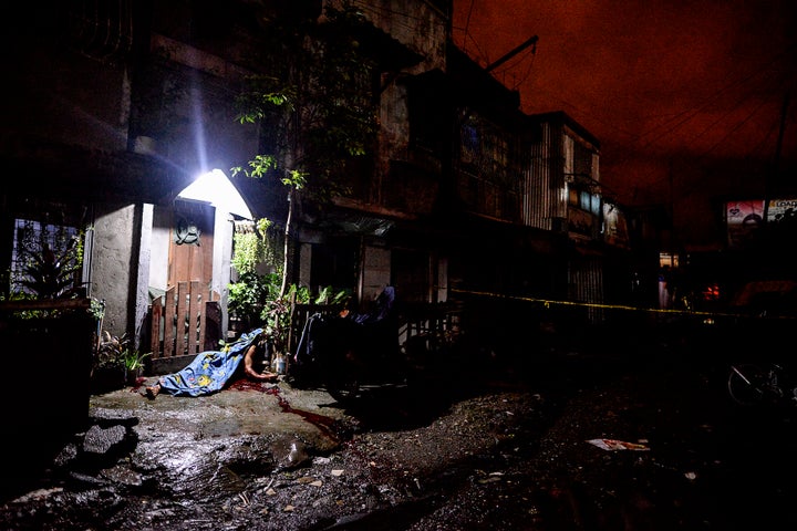 The corpse of a suspected drug pusher lies outside a house after he was shot dead following a police operation at a slum area