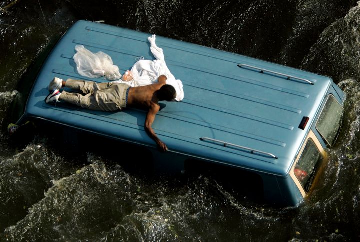 A man clings to the top of a vehicle before being rescued by the U.S. Coast Guard from the flooded streets of New Orleans, in the aftermath of Hurricane Katrina, in Louisiana in this September 4, 2005 file photo.