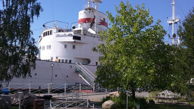 Museum visitors board ships anchored along the river