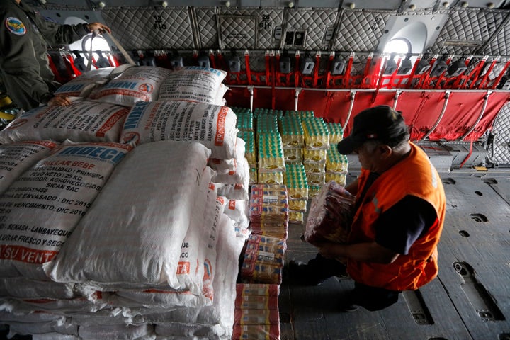 Members of Peru's National Institute of Civil Defense and Peru's Air Force load a cargo plane with aid to be delivered to the