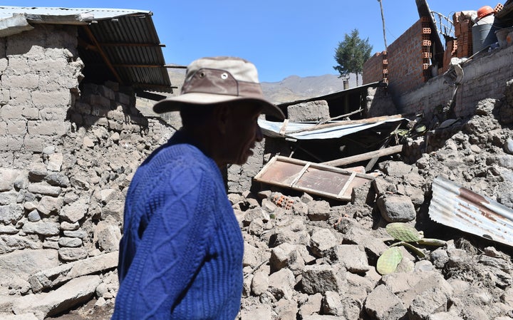 A man walks by toppled houses on August 15, 2016 in the Andean town of Yanque in southern Peru.