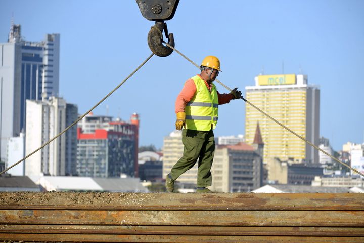 A Chinese construction worker helps build a new bridge against the skyline of Mozambique's capital Maputo April 15, 2016.