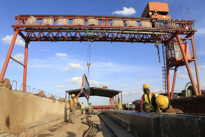 Workers are seen near a sign written in Chinese at the construction site of the Mombasa-Nairobi standard gauge railway (SGR)