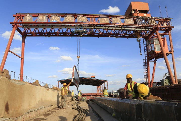 Workers are seen near a sign written in Chinese at the construction site of the Mombasa-Nairobi standard gauge railway (SGR) at Emali in Kenya October 10, 2015.