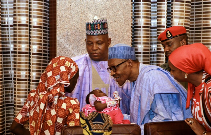 Amina Ali presents her child to Nigerian President Muhammadu Buhari after being rescued.