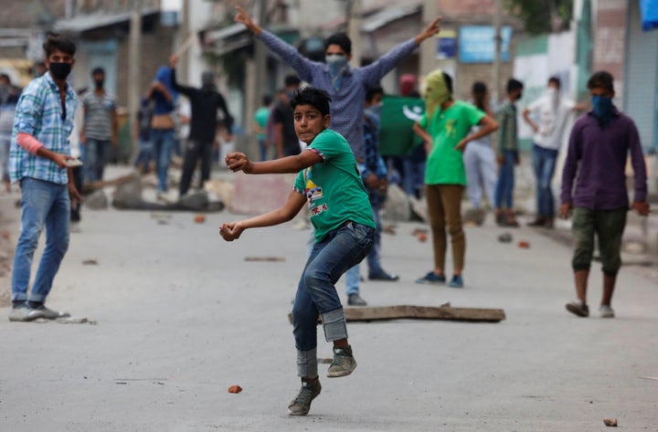 A protester throws stones towards the Indian police during a protest in Srinagar against the recent killings in Kashmir, August 9, 2016.