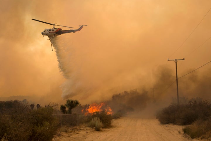 A helicopter makes a water drop at the Blue Cut wildfire in Phelan,California.