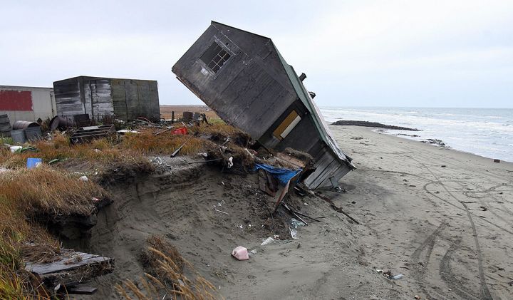 A home destroyed by beach erosion tips over in September 2006 in the Alaskan village of Shishmaref.