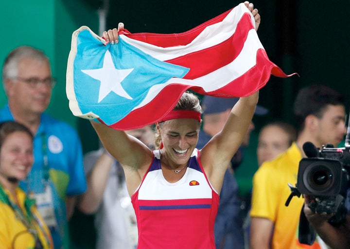 Monica Puig of Puerto Rico celebrates holding her country's flag after winning the gold medal match in the women's tennis competition at the 2016 Summer Olympics in Rio de Janeiro, Brazil, Saturday, Aug. 13, 2016.