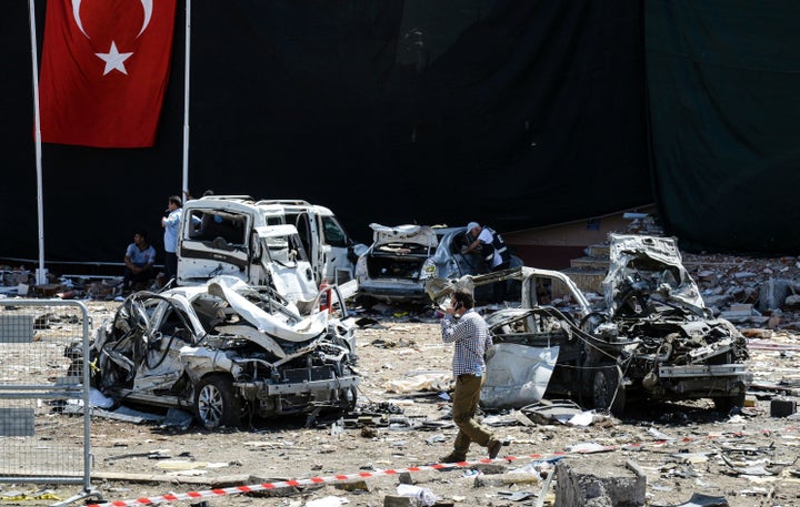 A man walks among the wreckage of vehicles as Turkish rescue workers and police inspect the blast scene following a car bomb attack in the Turkish city of Elazig.