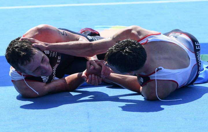 Alistair Brownlee (L) and his brother Jonny celebrate on the floor after the men's triathlon finish line
