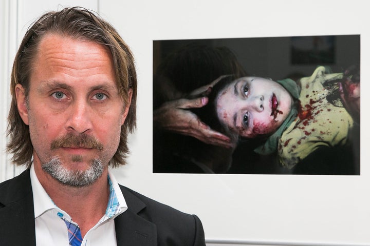 Swedish war photographer Niclas Hammarstraam poses with his photo of Dania, an 11-year-old girl who was hit by shrapnel while playing in Aleppo.