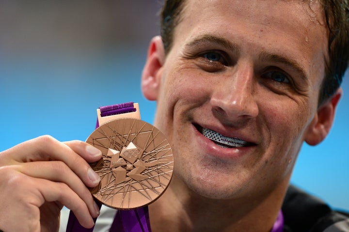 American swimmer Ryan Lochte poses at the 2012 Olympic with his bronze medal and silver grill.