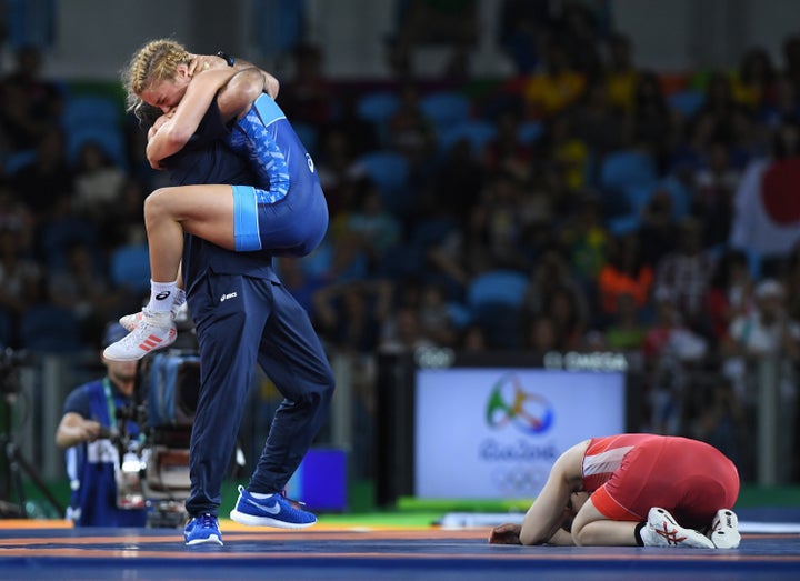 Saori Yoshida buries her face in the mat as U.S. wrestler Helen Maroulis celebrates her gold-medal win in the 53kg wrestling