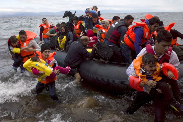 Refugees and migrants struggle to jump off an overcrowded dinghy on the Greek island of Lesbos. A record number of at least 430,000 refugees and migrants have taken rickety boats across the Mediterranean to Europe in 2015.