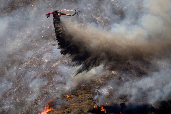 A firefighting helicopter makes a drop as firefighters try to gain control of the fire above homes along Cajon Boulevard at the Blue Cut Fire on August 18, 2016 near Wrightwood, California.