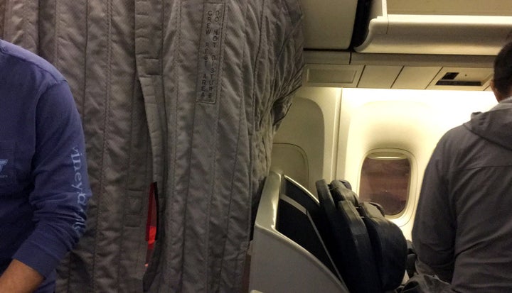 The curtain of the crew section of a passenger plane covers U.S. Swimmers Jack Conger and Gunnar Bentz during their overnight flight from Brazil to Miami.