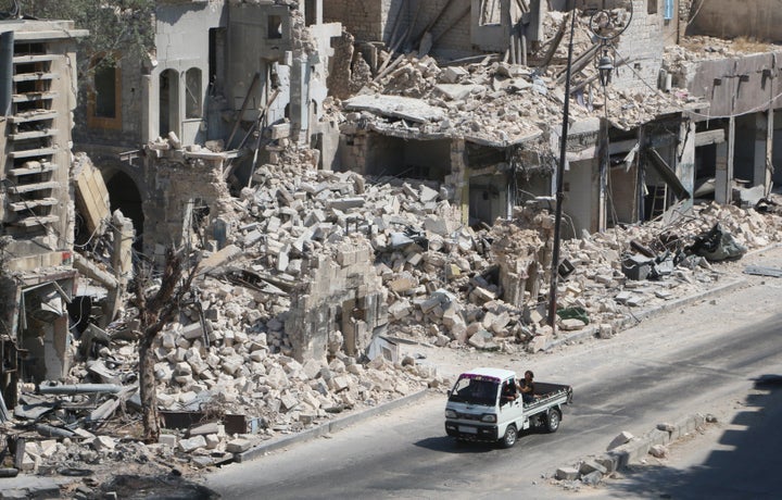 Russian cruise missiles targeted Syria on Friday. Pictured here, men ride on a pick-up truck past damaged buildings in t