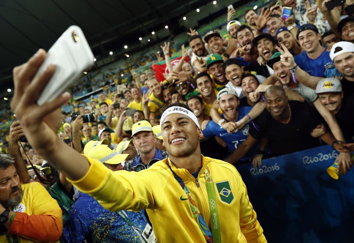 Brazil's forward Neymar poses for a selfie with fans at the Maracana stadium as they celebrate after the gold medal match between Brazil and Germany, Aug. 20, 2016.