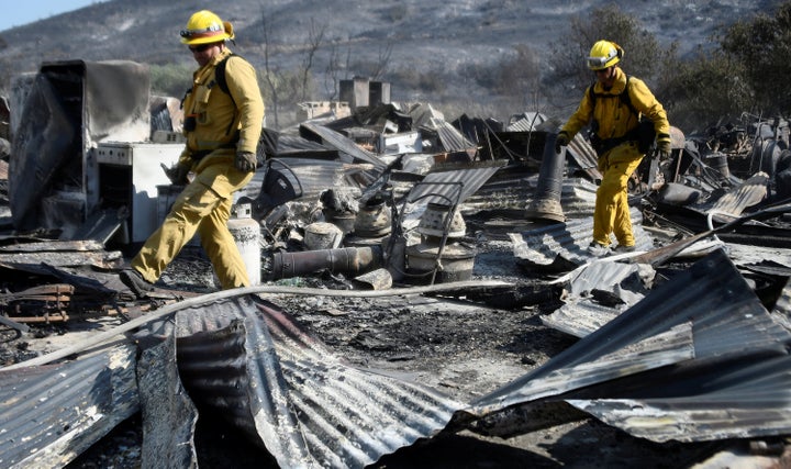 Firefighters walk over the remains of a barn destroyed by the so-called Blue Cut Fire in the San Bernardino National Forest i