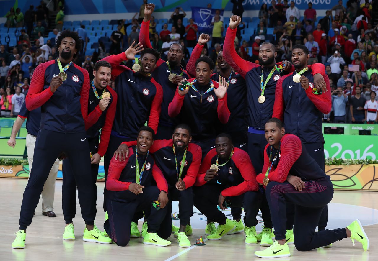 The United States Men's Basketball team celebrate with their gold medals while some mark the moment with their fists raised.