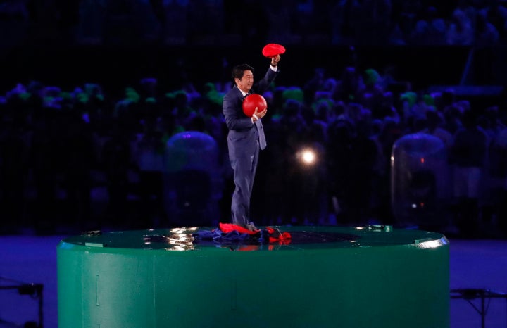 Japan's Prime Minister Shinzo Abe waves during the closing ceremony