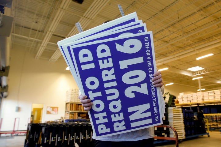 A worker carries a sign informing voters of a voter ID law intended to go into effect in 2016 in Charlotte, No