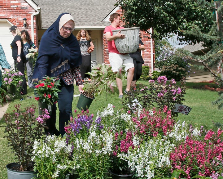 Sandra Rana, left, carries flowers to a memorial display on the lawn of the Jabara family in Tulsa, Aug. 19, 2016.