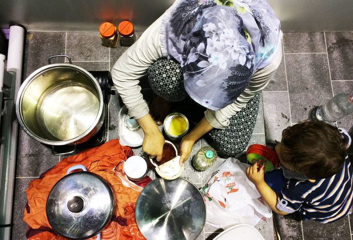 Bushra cooks food for her family inside her temporary living quarters at Berlin's Tempelhof refugee shelter.