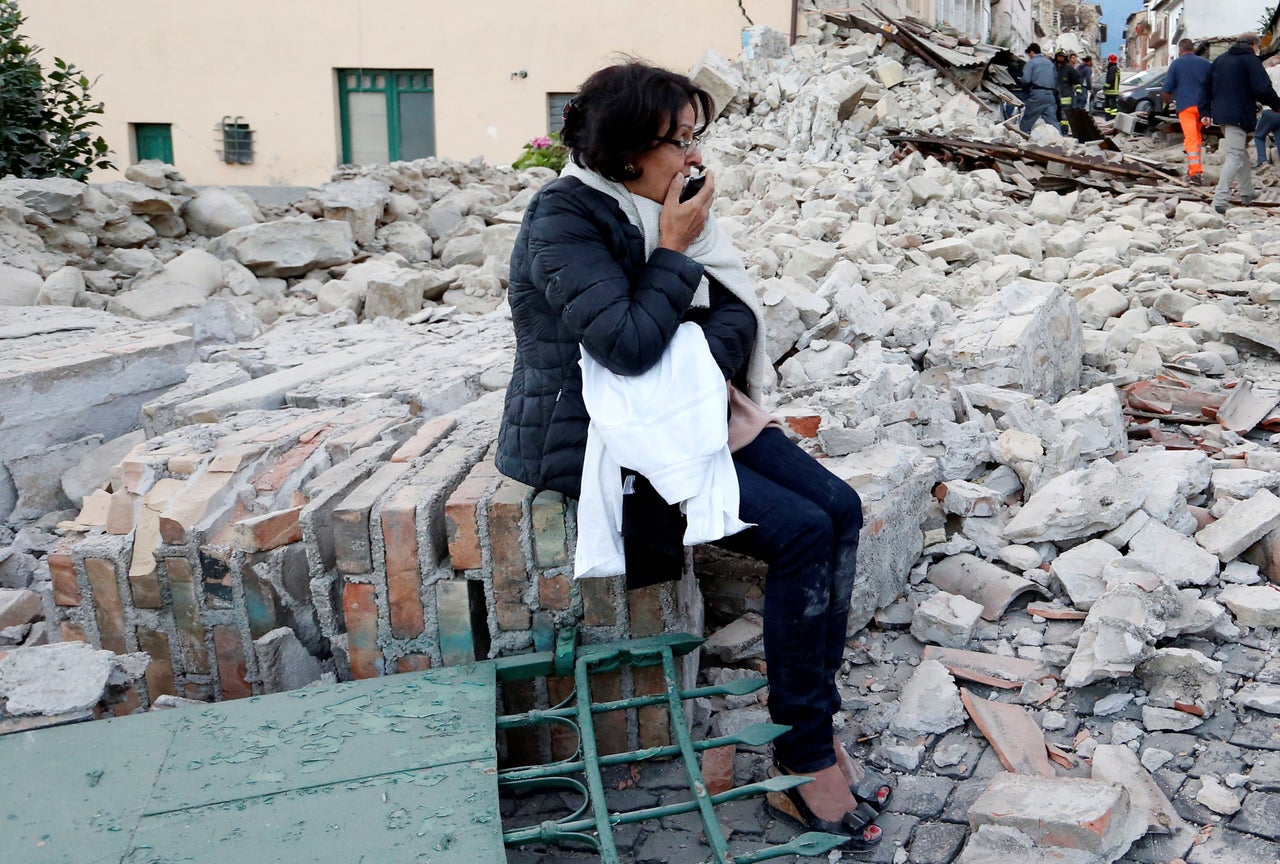 A woman sits amongst rubble following a quake in Amatrice, Italy, on Wednesday.