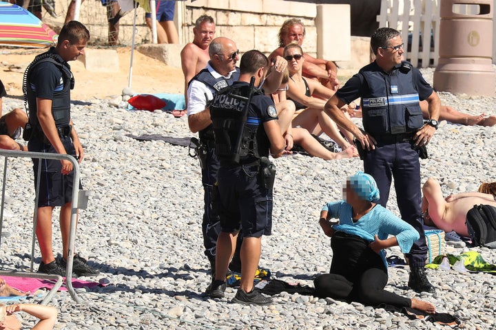 A woman was apprehended on the beach in Nice, France by four armed policemen.