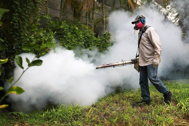 Carlos Varas, a Miami-Dade County mosquito control inspector, uses a Golden Eagle blower to spray pesticide to kill mosquitos in the Miami Beach neighborhood.