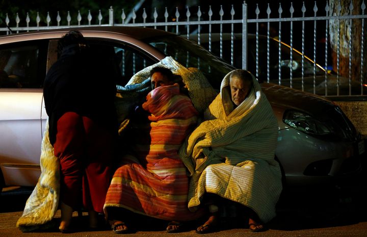 People layer themselves in blankets near a car as they prepare to spend the night in the open following an earthquake in Amatrice, Italy. 