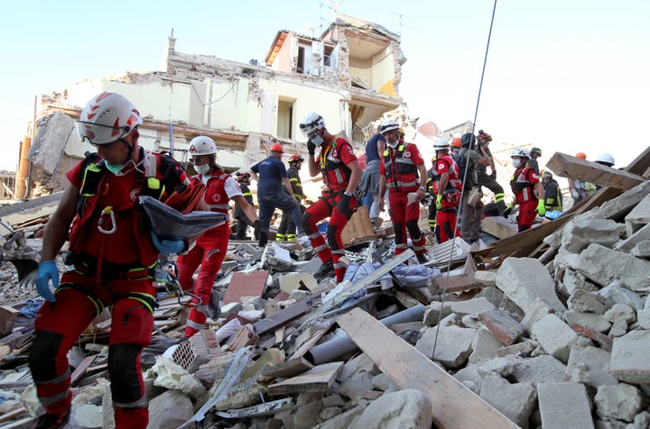 Rescuers walk through rubble following the earthquake in Amatrice, central Italy, August 24, 2016.