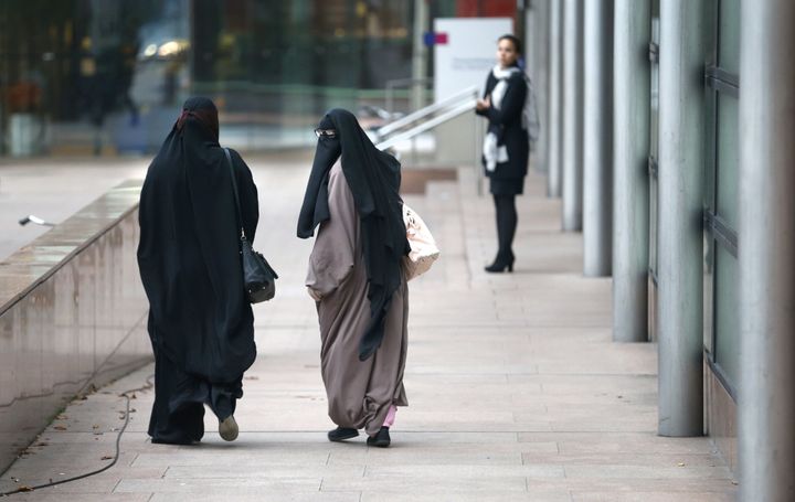 Women wearing burqas walk past the Palace of Justice in The Hague.