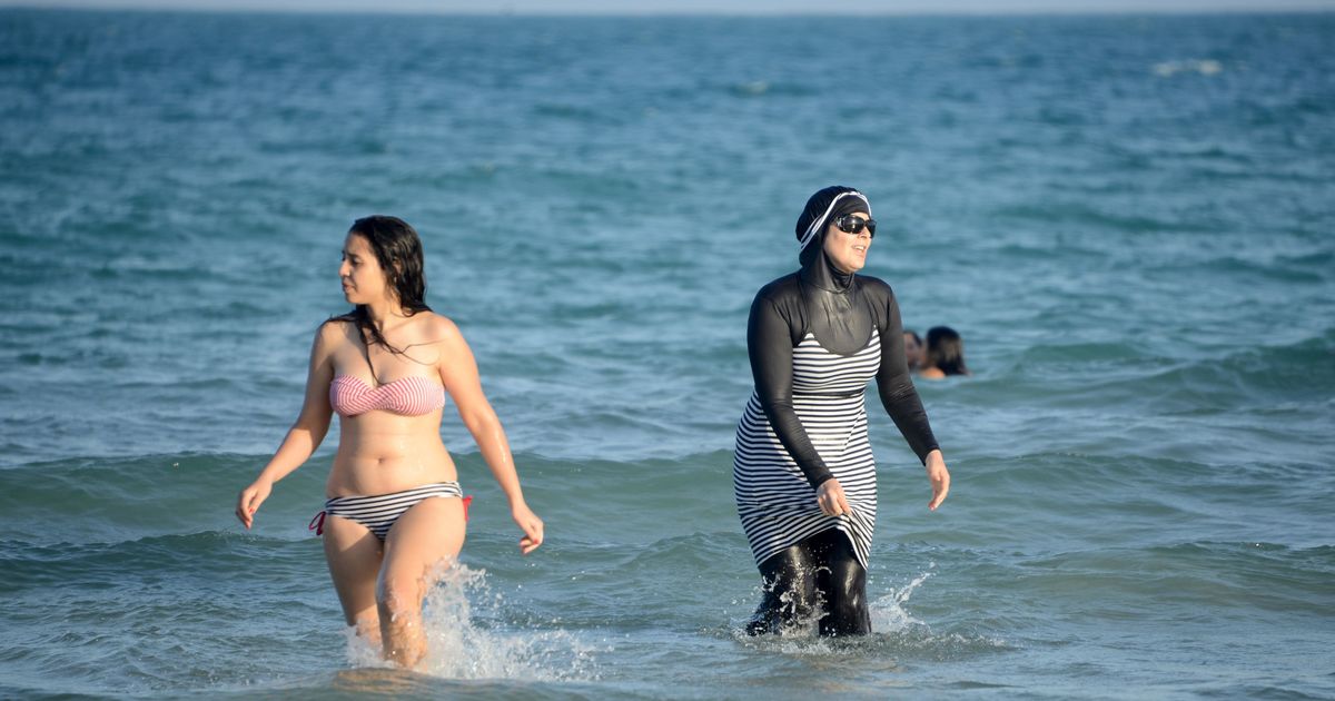 Slender young woman takes off her bikini and goes to swim in the sea
