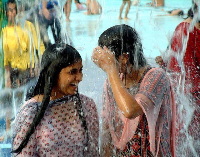 Girls smile as they enjoy a shower in a water park in the outskirts of Bhopal Madhya Pradesh.
