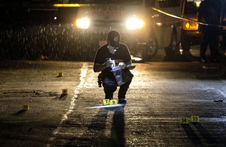 A Philippine Scene of the Crime Operative (SOCO) works at the scene where two suspects were shot dead following an encouter and shootout with police at a checkpoint along a highway in Manila on August 28, 2016.