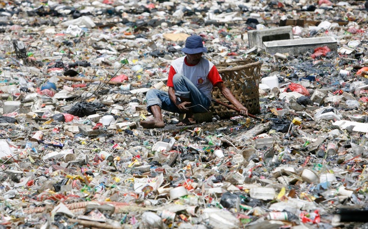 A man collects plastic goods in a river littered with garbage in Jakarta.