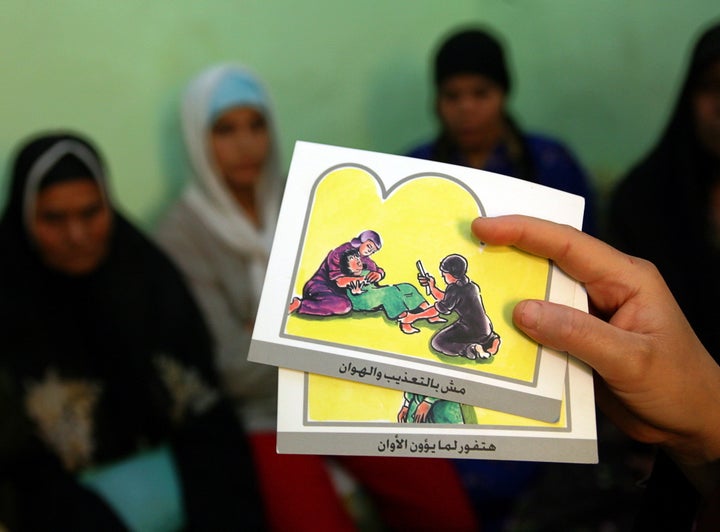 A counsellor holds up cards used to educate women about female genital mutilation (FGM) in Egypt, June 13, 2006. FGM is