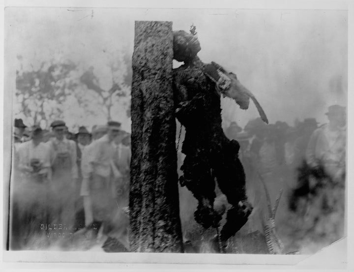 A crowd of people stands to watch the lynching by burning of Jesse Washington whose charred corpse leans chained to the trunk of a tree. Waco, Texas. (Photo by Gildersleeve/Library of Congress/Corbis/VCG via Getty Images)