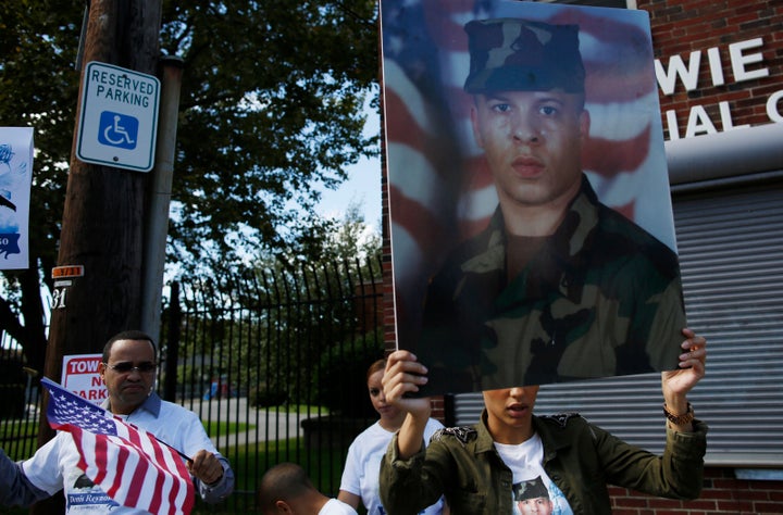 A woman holds a picture of Denis Reynoso, who was fatally shot by police. 