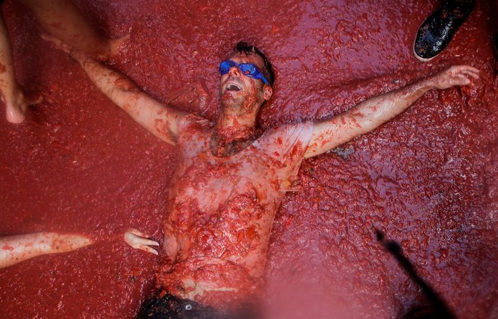 A reveller lies in tomato pulp during the annual Tomatina festival in Bunol near Valencia, Spain.