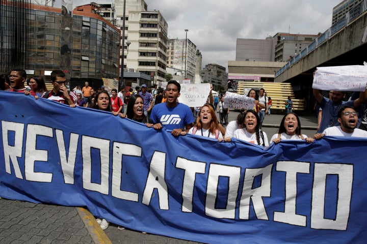 Student demonstrators hold a banner that partially reads "Recall" while gathering to protest against Venezuelan President Nic