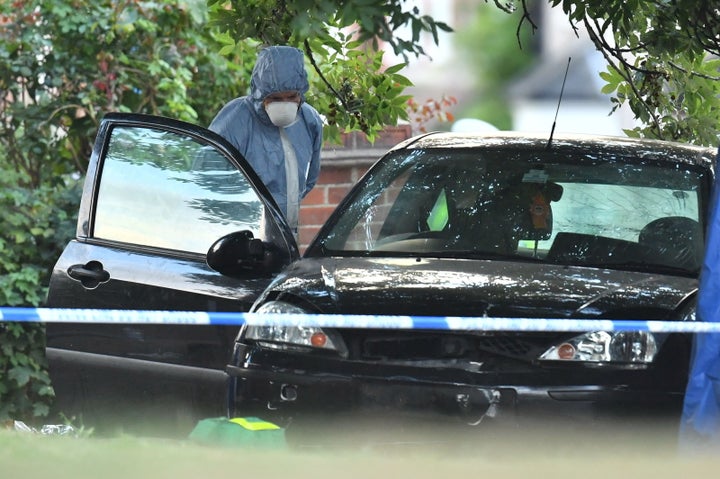 A forensic police officer examines a car at the scene in Lennard Road, Penge in south-east London