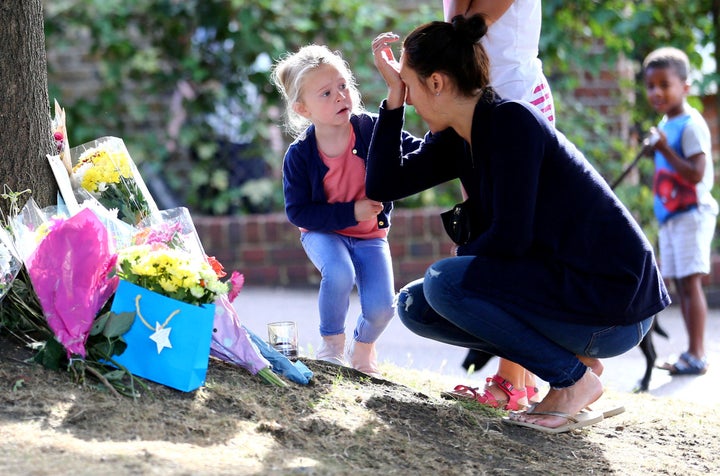 <strong>A woman is comforted by a child as she lays flowers at the scene</strong>